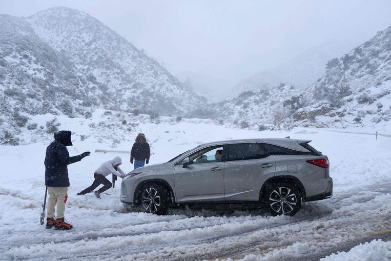 ‘Hulptroepen’ verlenen hulp bij een auto (zonder sneeuwkettingen) in de San Gabriel Mountains. Beeld AFP