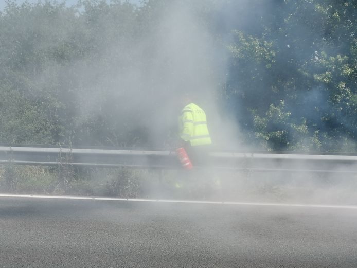 De chauffeur doet zijn best met een brandblusser uit zijn vrachtwagen maar kan het vuur niet doven langs de A12.