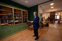 Wim Juch bij de bibliotheek met daarachter de living, ofwel de ontmoetingsruimte. Hij heeft in de boekenkast ook een aantal eigen boeken neergezet.
