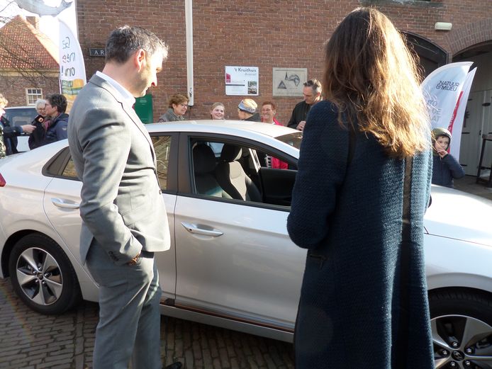 Wethouder Roland van Vugt en gedeputeerde Anne-Marie Spierings bekijken een van de elktrische deelauto's.