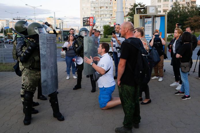 Een man zit op zijn knieën voor de oproerpolitie in de Wit-Russische hoofdstad Minsk. De zwaarbewapende politie was in grote getale aanwezig in de stad, maar dat hield heel wat demonstranten niet tegen om de straat op te komen.