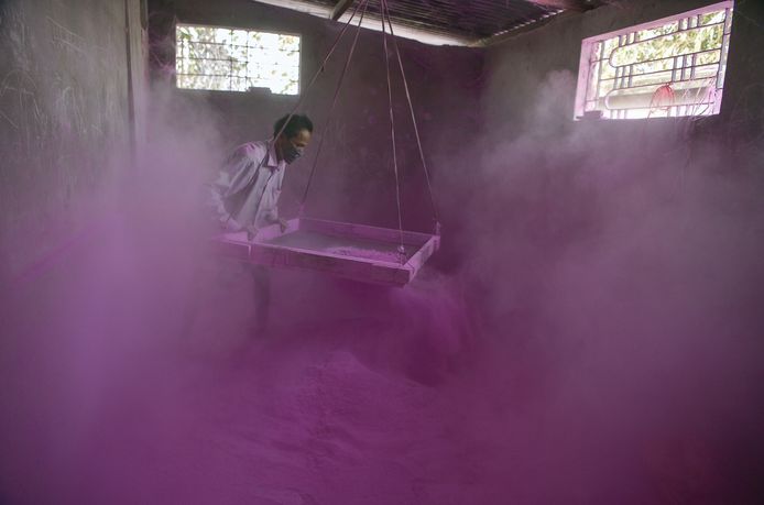 Een Indiase werknemer zeeft gekleurd poeder dat gebruikt gaat worden voor het komende Holi festival in een fabriek in Fulbari. FOTO:  Diptendu Dutta