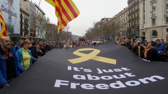 Pro-onafhankelijkheidsbetogers dragen een spandoek met de tekst: 'Het gaat om onze vrijheid' door de straten van Barcelona tijdens hun protest tegen de arrestatie van hun vroegere regiopremier Puigdemont in Duitsland.