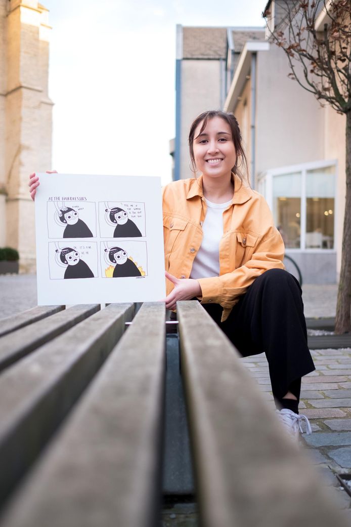 Christina De Witte met een comic van haar hand op een bankje naast de kerk van Onze-Lieve-Vrouw-over-de-Dijle.