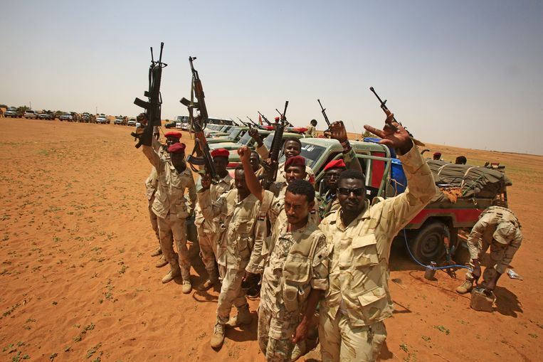 Leden van de Soedanese RSF-militie juichen. Ze hebben tientallen Afrikanen gevangen die de grens tussen Soedan en buurland Libië wilden oversteken.  Beeld AFP