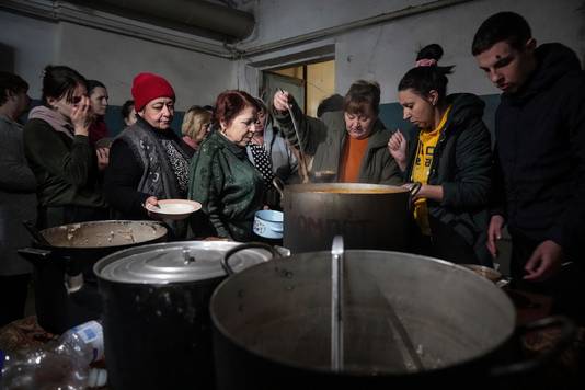 Mensen delen soep in een geïmproviseerde schuilkelder in Marioepol.