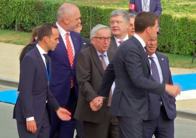 Mark Rutte neemt Jean-Claude Juncker bij de hand als blijkt dat de voorzitter van de Europese Commissie nauwelijks op de been kan blijven. Het gebeurde woensdagavond tijdens een Navo-evenement in het Brusselse Jubelpark. Rechts achter Rutte is de Portugese premier Costa half zichtbaar.  Beeld AP