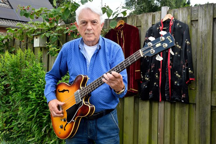 Schrijver/samensteller Jacques Smulders met zijn basgitaar uit '67 en achter hem zijn flower power-outfit.