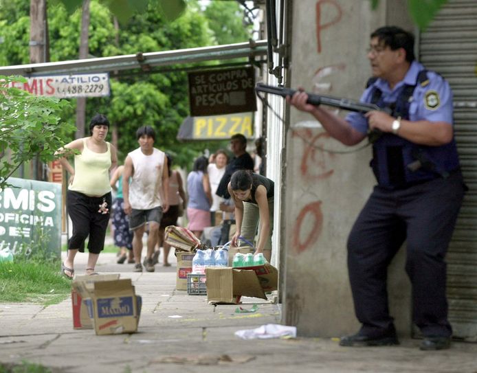 Archiefbeeld. Een politie-agent probeert een buurtsuper te beschermen tegen plunderaars. (19/12/2001)