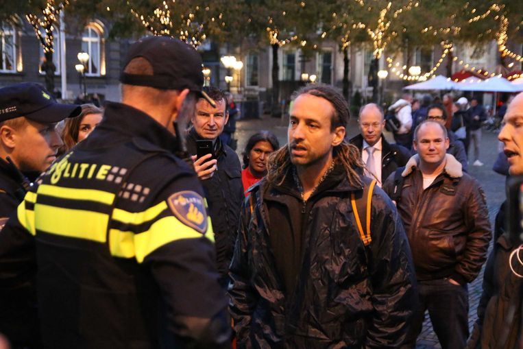 Willem Engel van actiegroep Viruswaarheid is in discussie met een politieagent tijdens een onaangekondigd protest. Beeld ANP