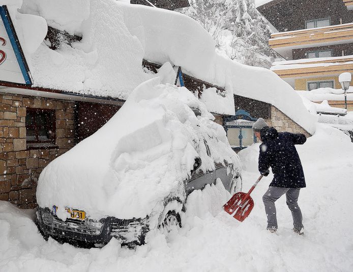 Een toerist probeert zijn auto sneeuwvrij te maken in  Filzmoos.
