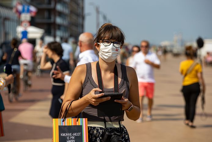 Een vrouw draagt een mondmasker op de zeedijk in Knokke-Heist. Nee, jodium in de zeelucht remt het virus niet af en nee, het dragen van een mondmasker zal je geen zuurstofgebrek opleveren.