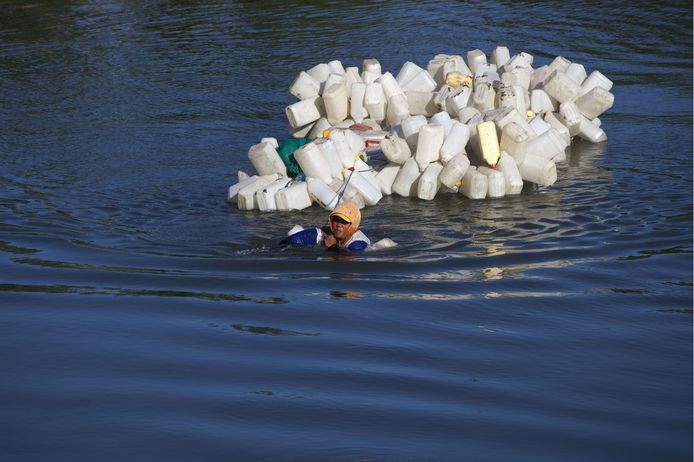 De 46-jarige Hasria uit Tinambung in West Sulawesi zwemt met zo'n 220 lege jerrycans 4 km stroomopwaarts om deze te laten vullen met schoon drinkwater voor het dorp. Foto Yusuf Wahil