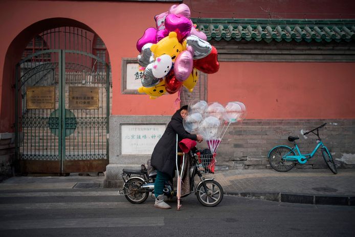 Een vrouw verkoopt ballonnen in Beijing vanaf haar brommertje. Foto Fred Dufour