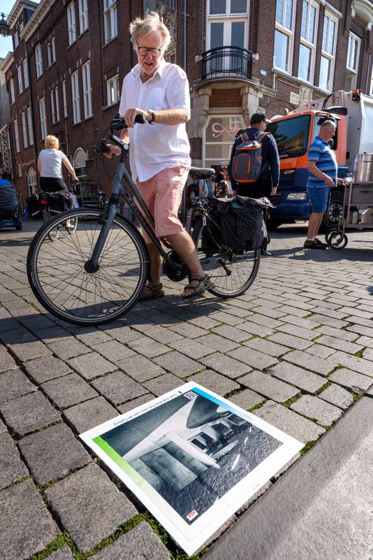 Een vrouw  bekijkt één van de opvallende stoeptegel-stickers op de Markt in Den Bosch.