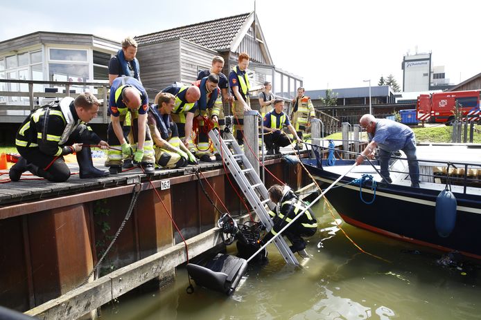 Klaas Klos (rechts met pikhaak) helpt de brandweer om de scootmobiel uit het water van de Bovenhaven in Kampen te tillen. Met diezelfde pikhaak redde hij even daarvoor het leven van de scootmobieler.