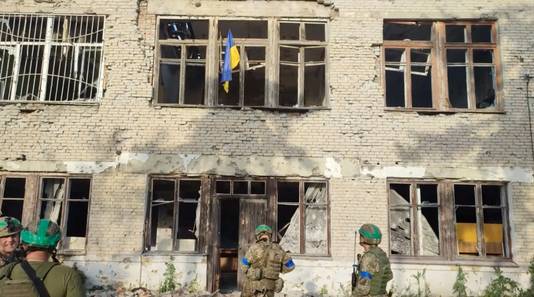 Oekraïense soldaten hangen de Oekraïense vlag aan een gebouw in Blahodatne.