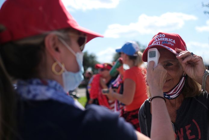 Een vrijwilliger checkt de temperatuur van een vrouw die Trumps rally in Florida wil gaan bijwonen.