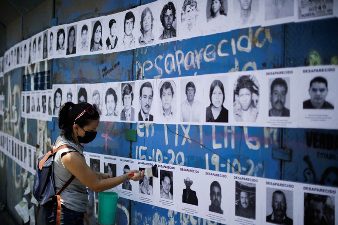 Een familielid van een vermist persoon plakt een foto van haar geliefde op een muur die gewijd is aan alle vermiste personen in Mexico.
