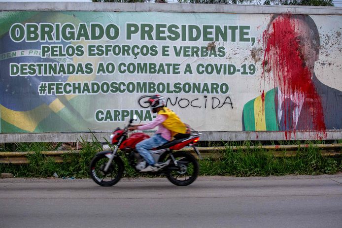 Het gezicht van president Jair Bolsonaro op een reclamedoek is beklad, en demonstranten plaatsten er het woord 'genocide' bij.