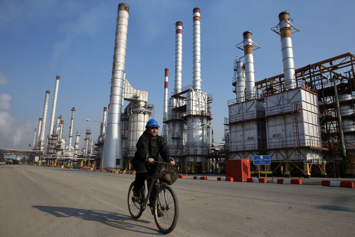 Een medewerker van de Iraanse olieraffinaderij ten zuiden van Teheran. De olieprijzen dalen mede doordat acht landen olie mogen blijven kopen van Iran.