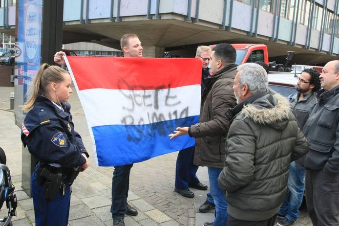 Een man met Nederlandse vlag met de tekst 'Geert bedankt' laat buiten het politiebureau een tegengeluid horen.