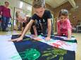 Verkeersactie bij basisschool De Kiem in Heesch. Kinderen stempelen hun handafdruk op een zebrapad-achtig spandoek.
Een opname uit 2020.