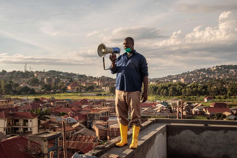 Gonzaga Yiga (49) op het hoogste gebouw van Kampala, de hoofdstad van Oeganda. Met een megafoon roept hij elke ochtend en avond adviezen rond waarmee de inwoners van de stad de verspreiding van het coronavirus tegen kunnen gaan.   Beeld Badru KATUMBA / AFP