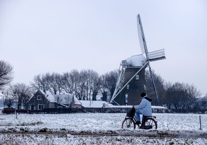 Een fietser is op weg naar school en rijdt voorbij de molen Johanna-Elisabeth in Vlierden.