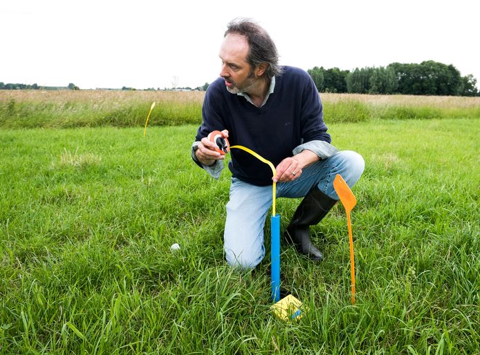 Rene Faber meet op het gehoor het grondwaterpeil op het weiland van boer Blonk  (Foto Marnix Schmidt)