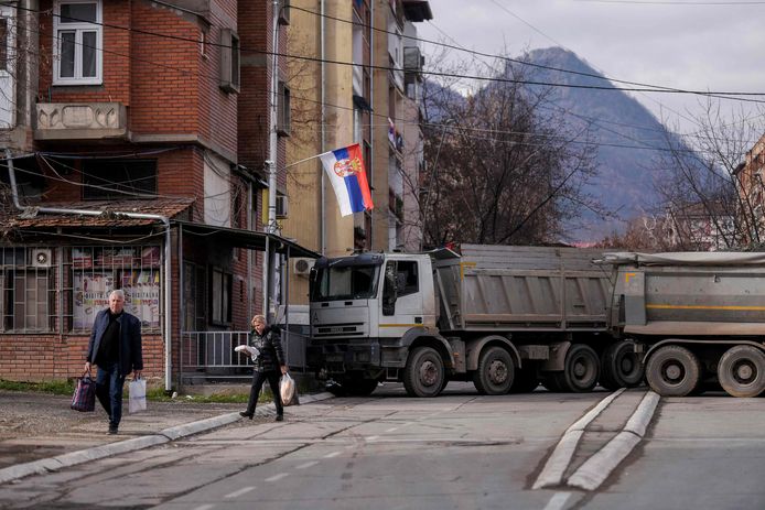 Voetgangers lopen langs een nieuwe wegbarricade die vandaag werd opgezet in de verdeelde stad Mitrovica.