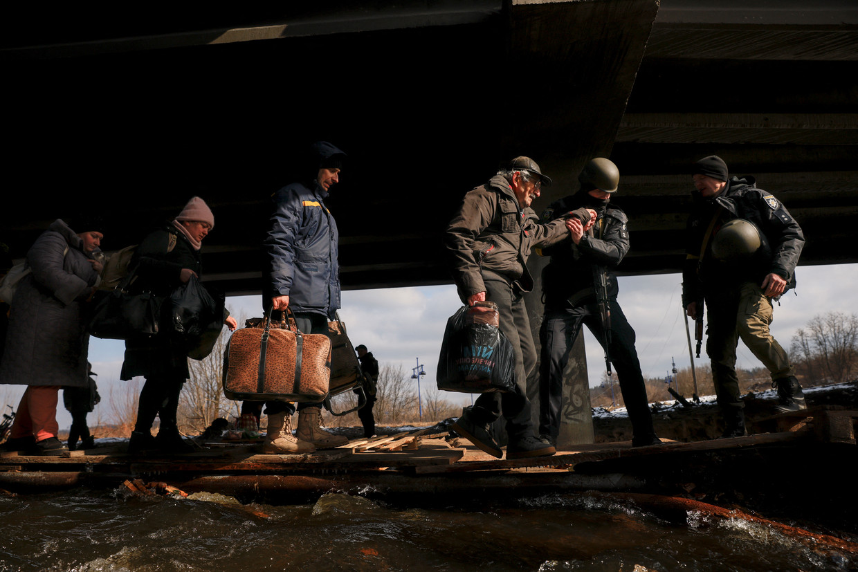 Mensen steken de rivier de Irpin over via houten planken, om het voorstadje te kunnen verlaten.  Beeld REUTERS