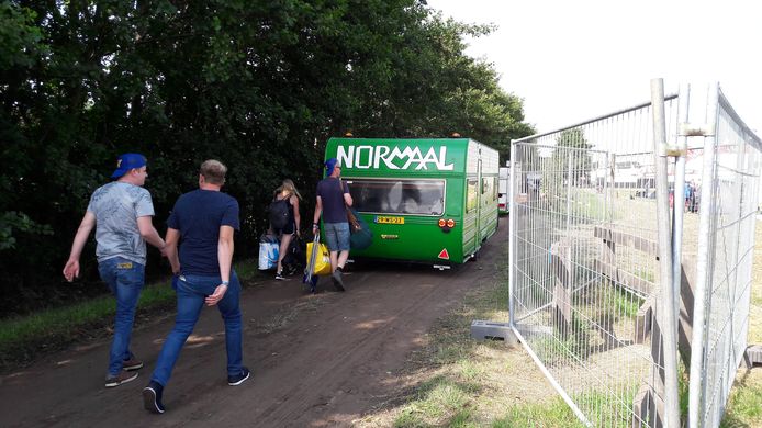 Mensen lopen richting de camping achter een caravan