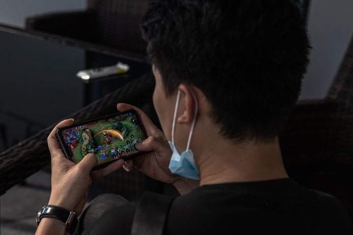 Een Chinese jongeman speelt het populaire spel Honor of Kings op zijn mobiele telefoon.