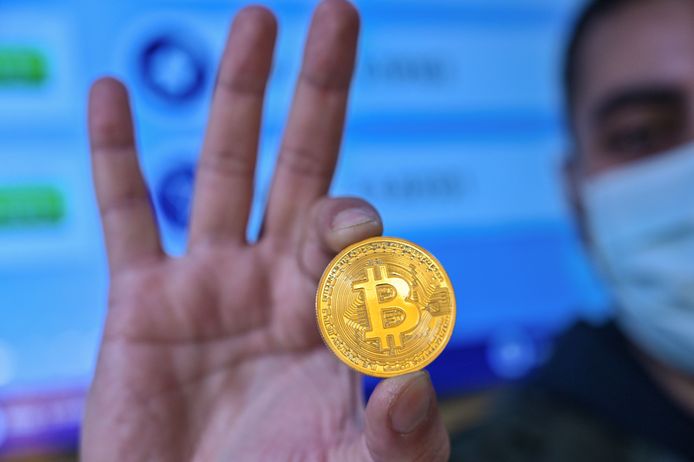 Een man houdt een bitcoinmunt vast. Een imitatie natuurlijk, want het is een digitale munteenheid.