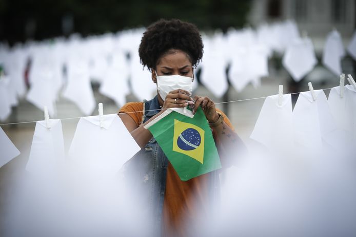 Een vrijwilliger helpt bij het ophangen van witte zakdoekjes ter nagedachtenis van de duizenden Braziliaanse coronadoden.