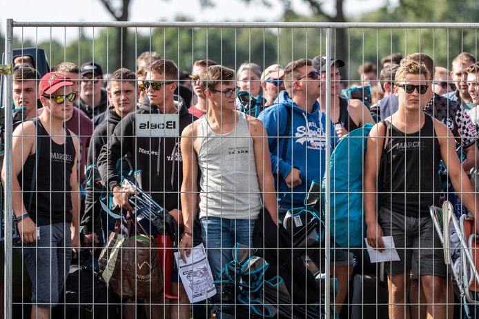 Mensen staan te wachten voor de hekken.