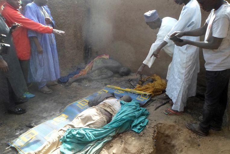 Mensen staan om het lichaam van een man en zijn kinderen, die werden vermoord bij de aanval van Boko Haram in het dorp Dalori, Nigeria Beeld DIO