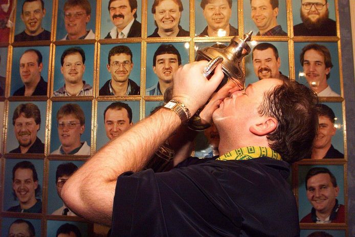 1999: Raymond van Barneveld wint het WK in Frimley Green en kust de trofee. Op de achtergrond de Hall of Fame, met de portretten van de winnaars van het Embassy World Darts door de jaren heen.