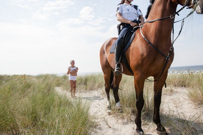 Een werk uit de tentoonstelling van Peter de Krom in de Rotterdamse Kunsthal. Deze foto is gemaakt op 15 augustus 2012. In Hoek van Holland is vanaf dat jaar het duingebied achter het naaktstrand afgesloten met een hekwerk. De mannen die hier juist graag naaktlopen, in de volksmond ook wel ‘stokstaartjes’ genoemd, verplaatsen zich massaal naar het nabijgelegen publieke duin. Wanneer strandgangers en met name strandhuiseigenaren klagen over onzedelijk gedrag, grijpt de politiek in. Politie te paard en in burger treedt op tegen de naaktlopers. Blote billen worden bekeurd. Deze vrouw komt vragen of ‘dit’ nog wel mag.