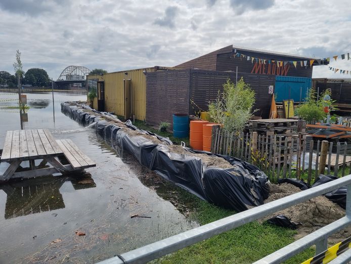 De wal met zandzakken houdt het voorlopig nog bij Meadow op het Deventer Stadsstrand. Wel moet er water weggepompt worden dat onder de zandzakken door komt sijpelen.
