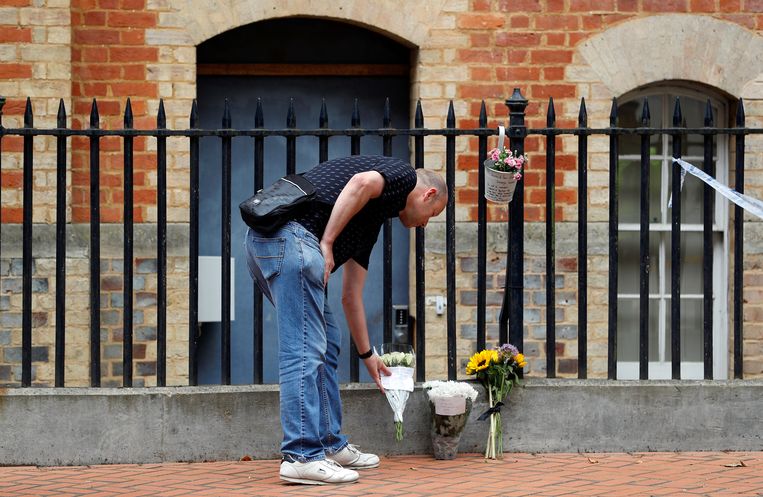 Een man plaatst zaterdag bloemen bij de plek waar de aanslag werd gepleegd in het Britse Reading. Beeld Reuters