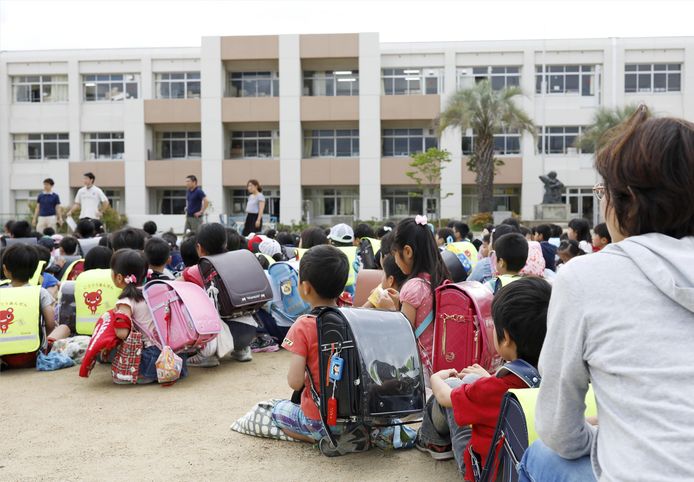 Kinderen zitten op het schoolplein, nadat ze uit hun schoolgebouw geëvacueerd werden na de aardbeving in Ikeda, in de Osaka prefectuur in west-Japan.
