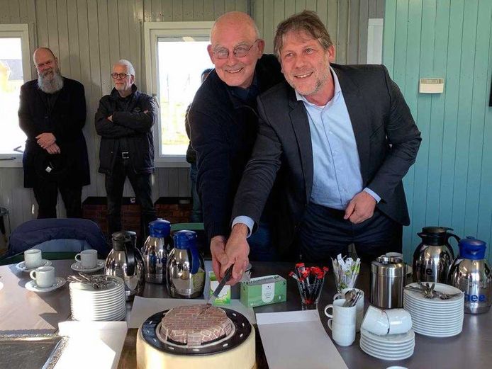 Wethouder Ro van Doesburg (rechts) zet samen met kunstenaar Hans van Lunteren het mes in een taart met daarop de rotonde.