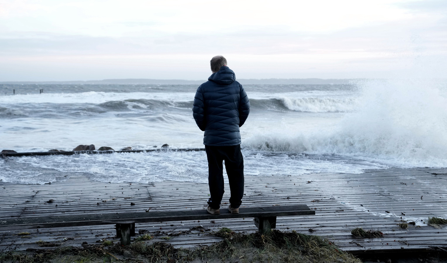Un homme regarde le rivage après que la tempête Malik a fait monter le niveau des eaux au port de Hornbaek, en Zélande du Nord, au Danemark, le 30 janvier 2022.