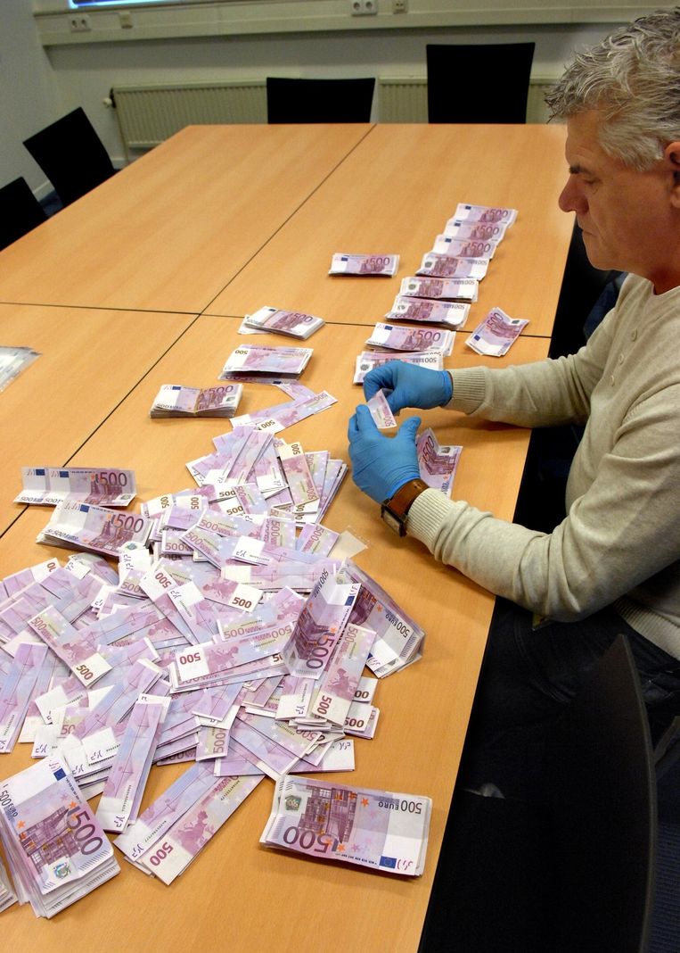 Een rechercheur onderzoekt of er sporen zitten op 500 eurobiljetten. Beeld anp
