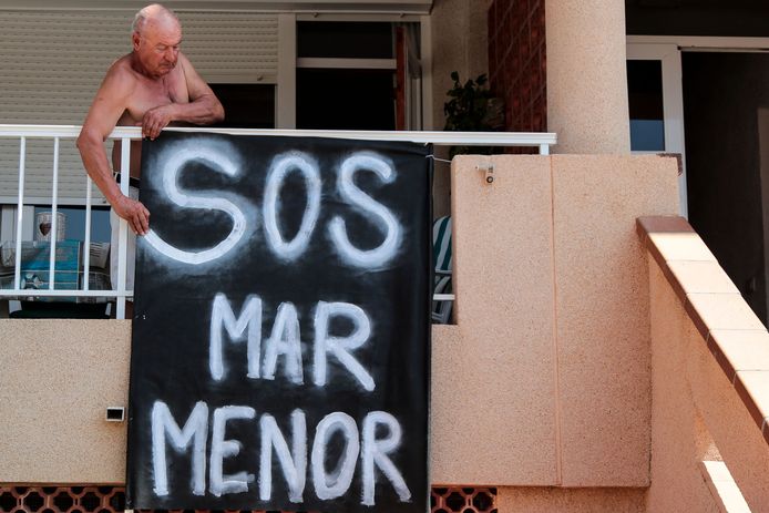 Un homme attache une bannière sur sa terrasse à Puerto Bello de la Manga, près de Murcie, le 25 août 2021.