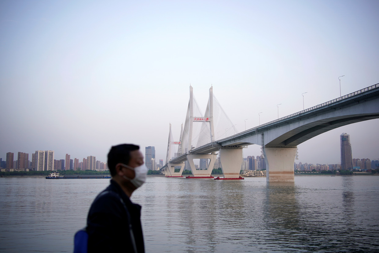 Een man met een mondkapje bij de brug over de Yangtze na het opheffen van de lockdown in Wuhan.