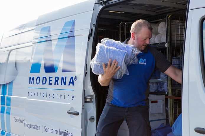 Een medewerker van wasserij Moderna haalt spullen - nee, geen vaccins - uit zijn busje.