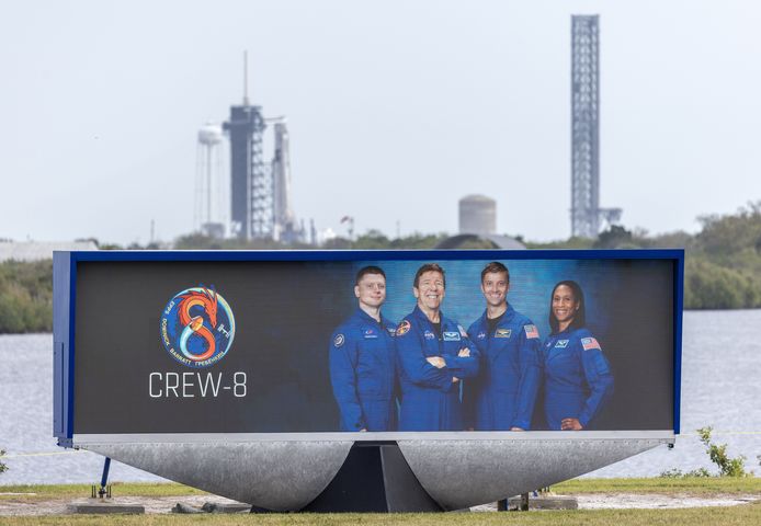 Leden van de Crew-8 op een poster, met op de achtergrond het ruimtevaartuig SpaceX Dragon Endeavour op een Falcon 9-raket.